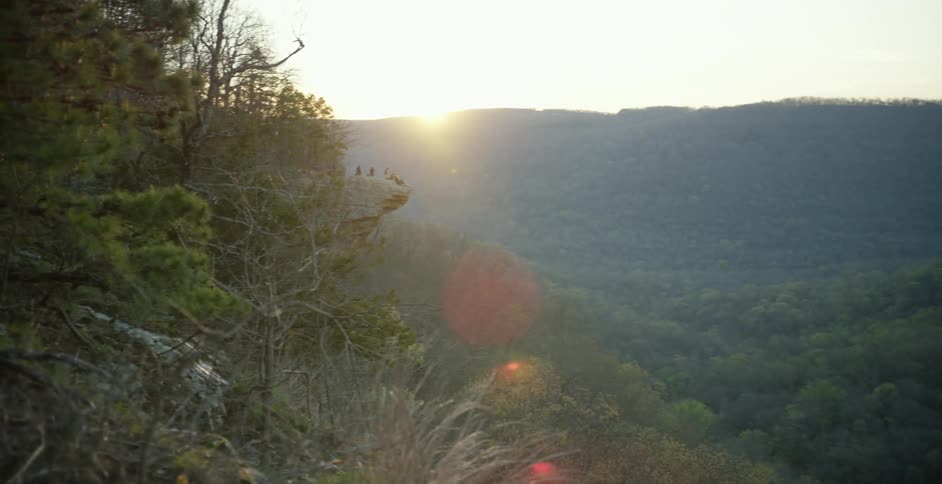 The sun is peeking over a mountain beyond a valley