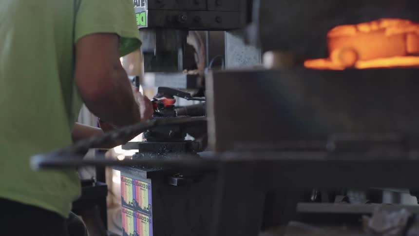 Person shaping a hot iron on a machine