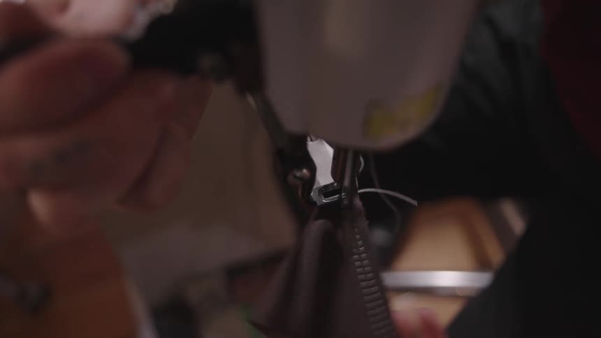 An artisan sews a piece of fabric on a sewing machine