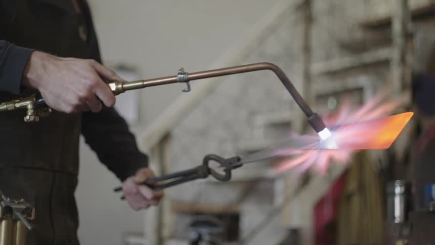 A man is heating a blade with a torch