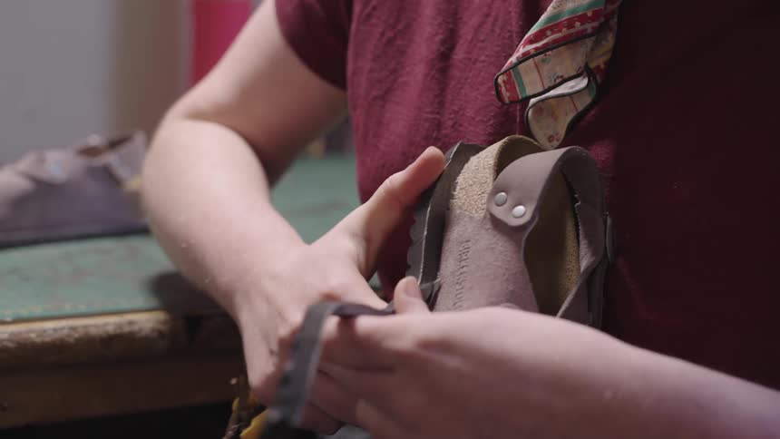 A craftsman trims the rubber sole of a shoe