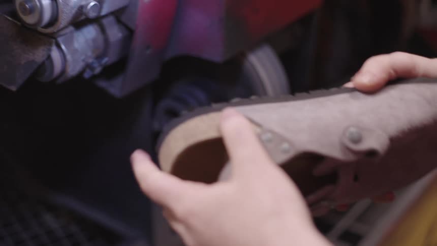 Womans hand refining the sole of a shoe on a machine