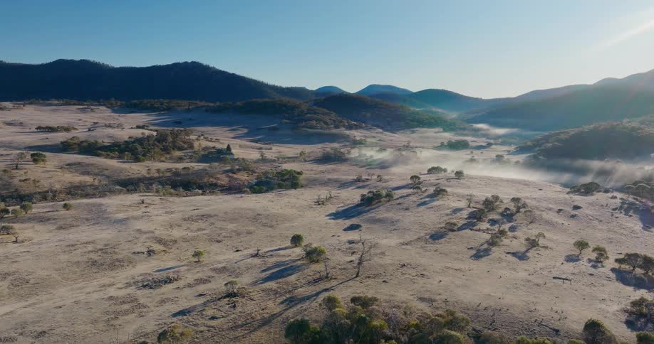 Aerial view of a savannah region with forested mountains in the background