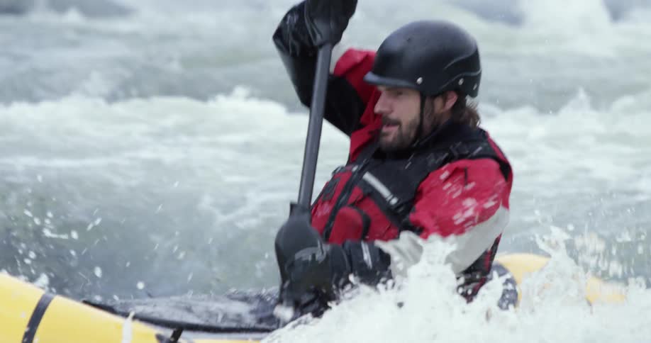 A man paddles a rubber raft in whitewater