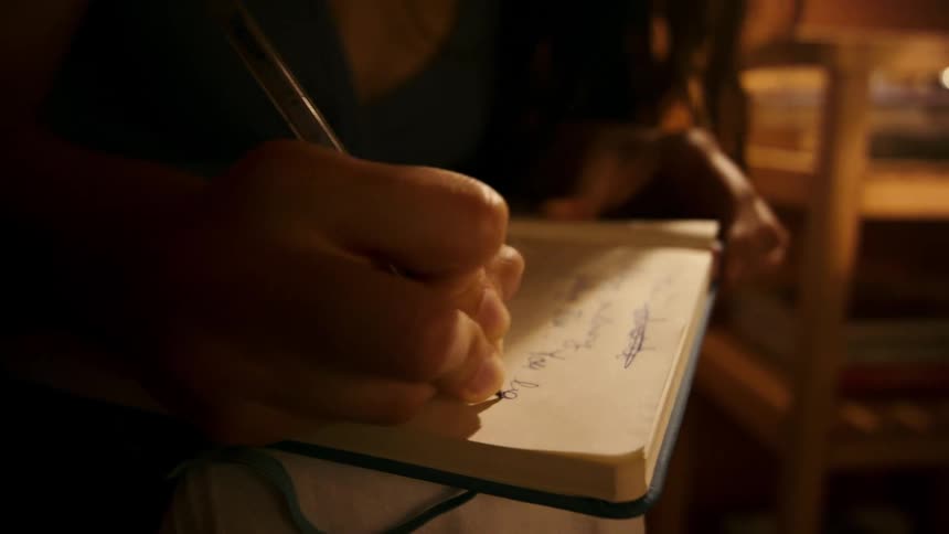 Close up of a girl writing thoughts angrily in a journal