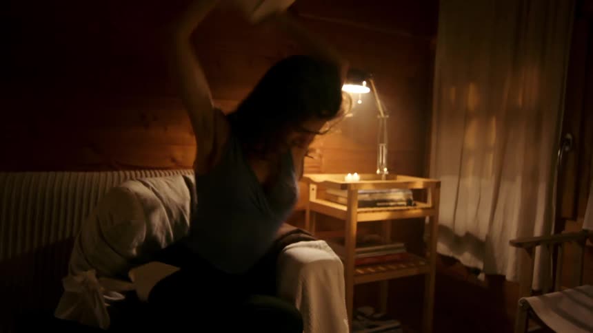 Very distraught young woman tearing a book apart then throwing it in a darkened room