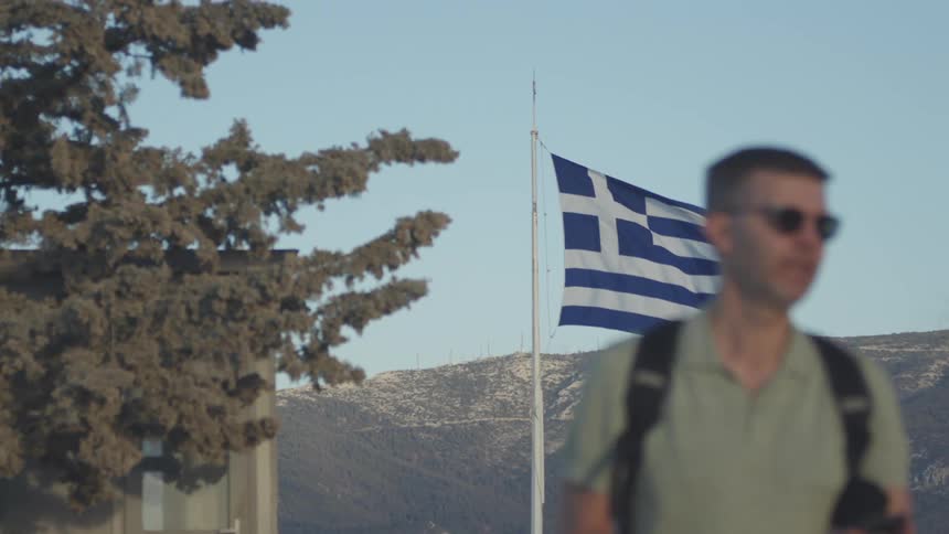 Two tourists walk past a large flag
