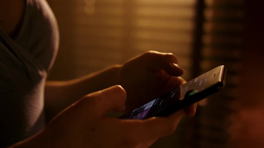 A woman browses her smartphone in a cozy room
