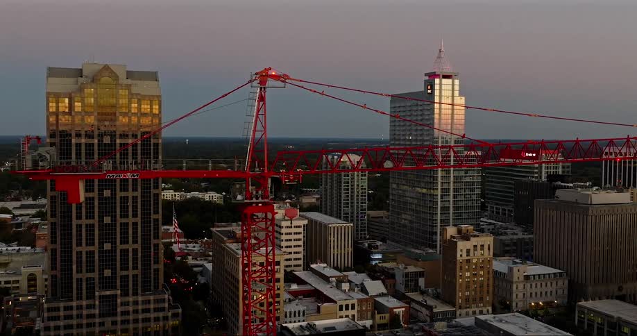 A flag dangles from a crane in front of a city