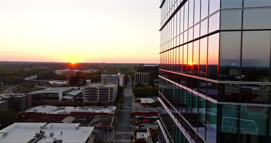Large glass building towers over other buildings and traffic below