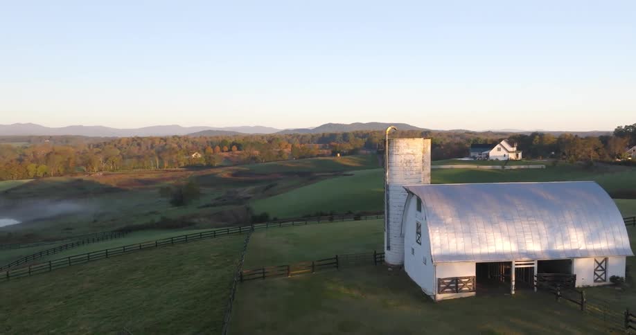 Aerial view of a farm surrounded by vegetation with mountains on the horizon