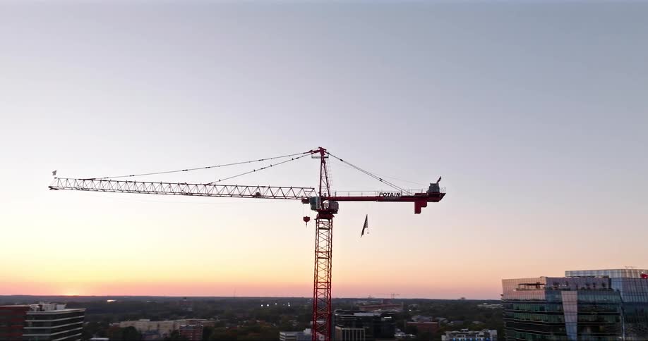 Large construction crane against a twilight sky towering over a cityscape with buildings in the background