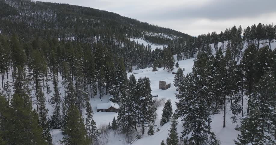 Aerial panorama of cabins in a snowcovered mountainous area with conifers