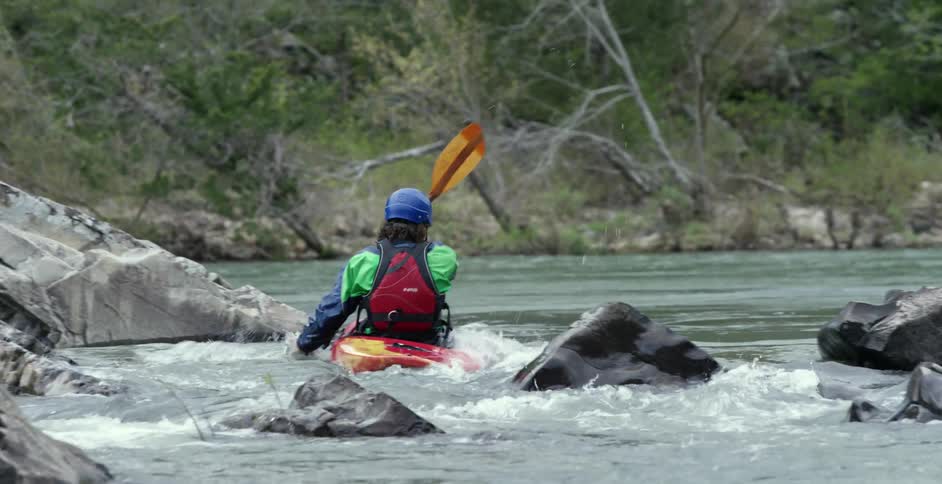 A kayaker enters a river and paddles