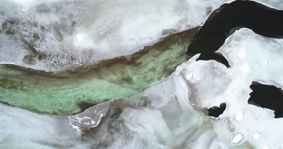 Aerial view of a frozen landscape with a greenish river