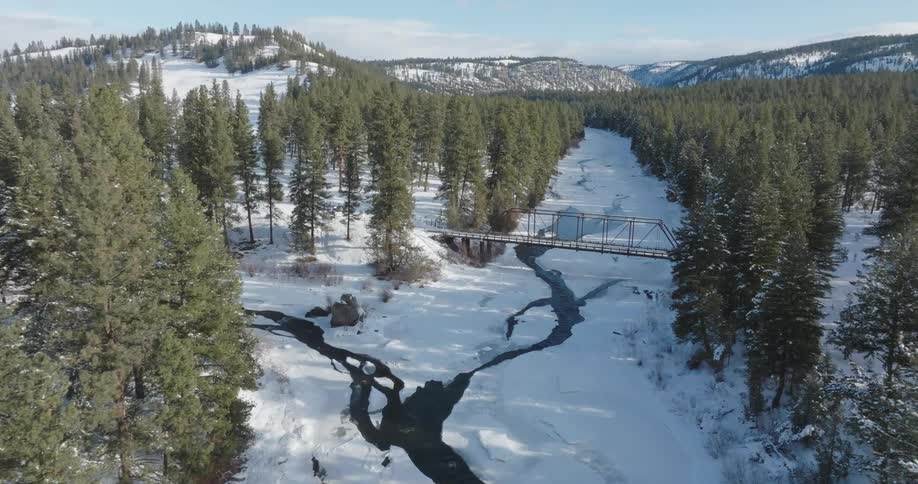 Aerial landscape on a bridge above a river in a dense coniferous and snowy area