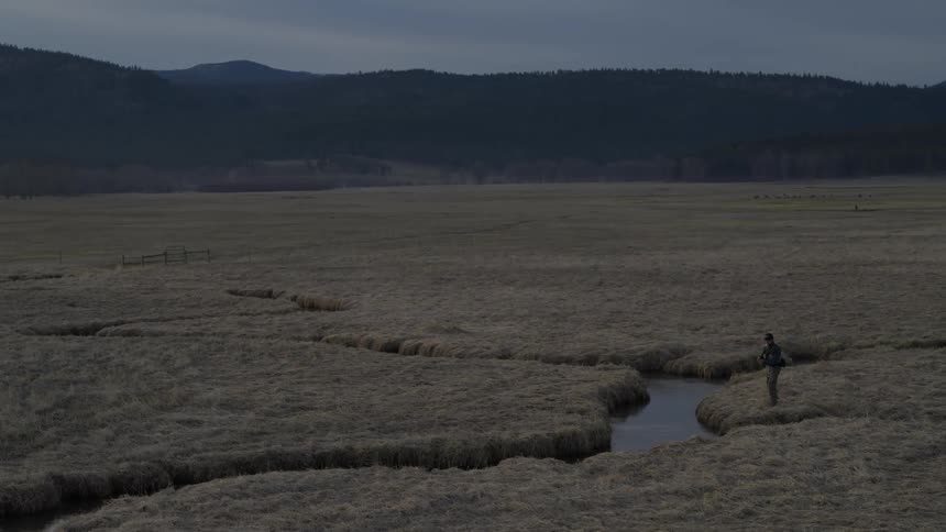 Person standing near the creek in front of the mountains
