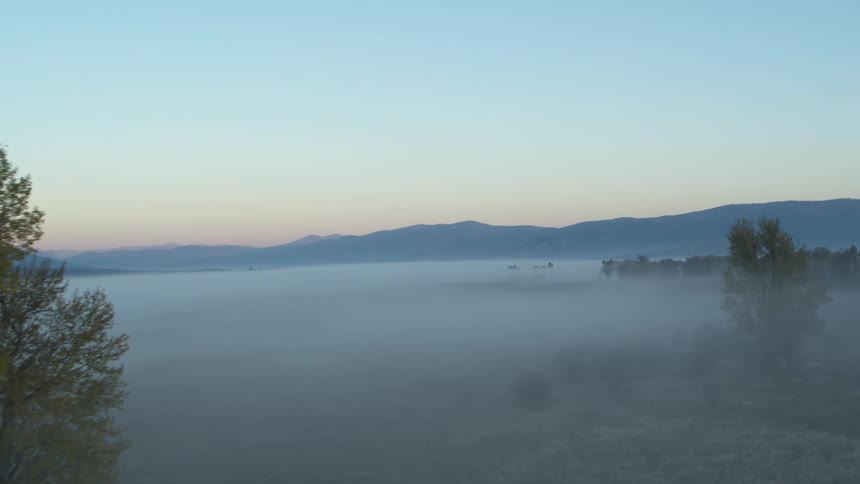 Landscape at dawn with mist covering the ground between rolling hills and a clear sky above