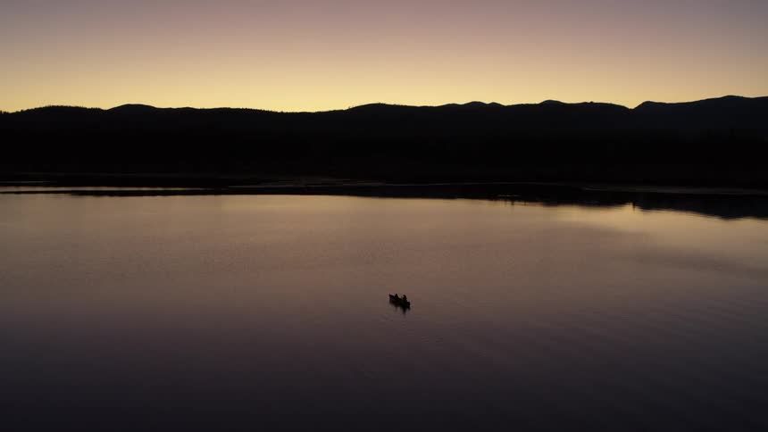 Silouhette of a kayak paddling on a lake an dawn