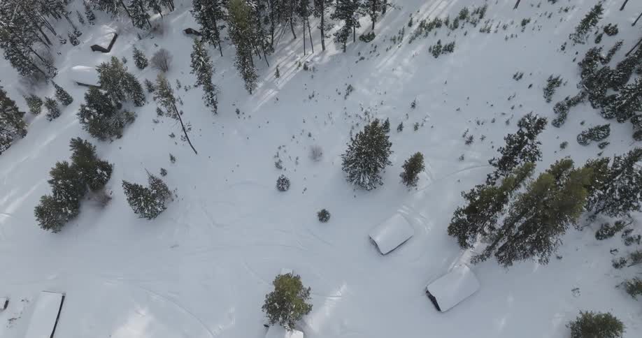 Aerial view of a snowy landscape with several cabins surrounded by trees