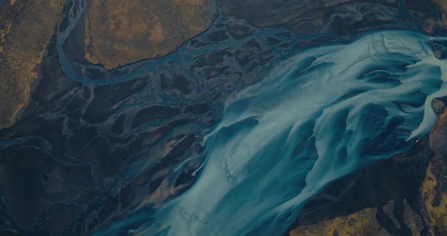 A winding river of glacial meltwater snakes through a dark barren landscape