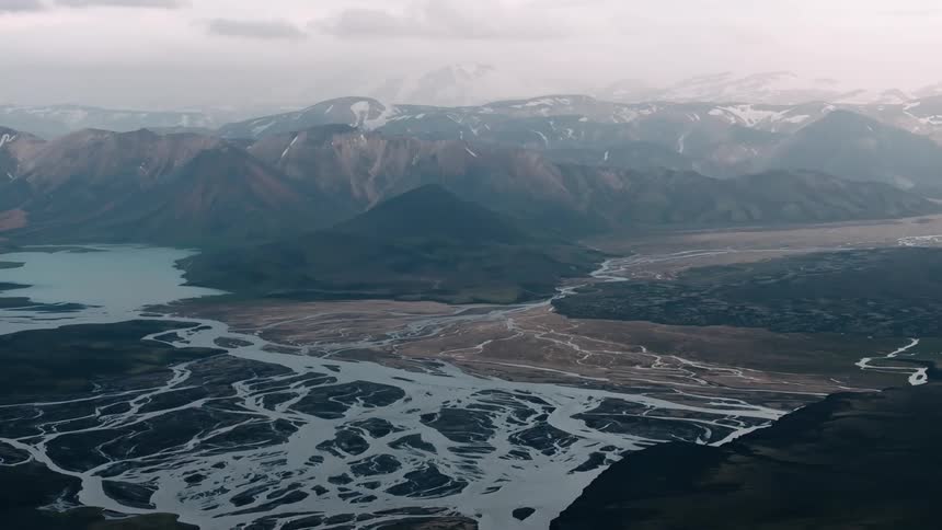 A vast winding river snakes its way through the rugged snowcapped mountains