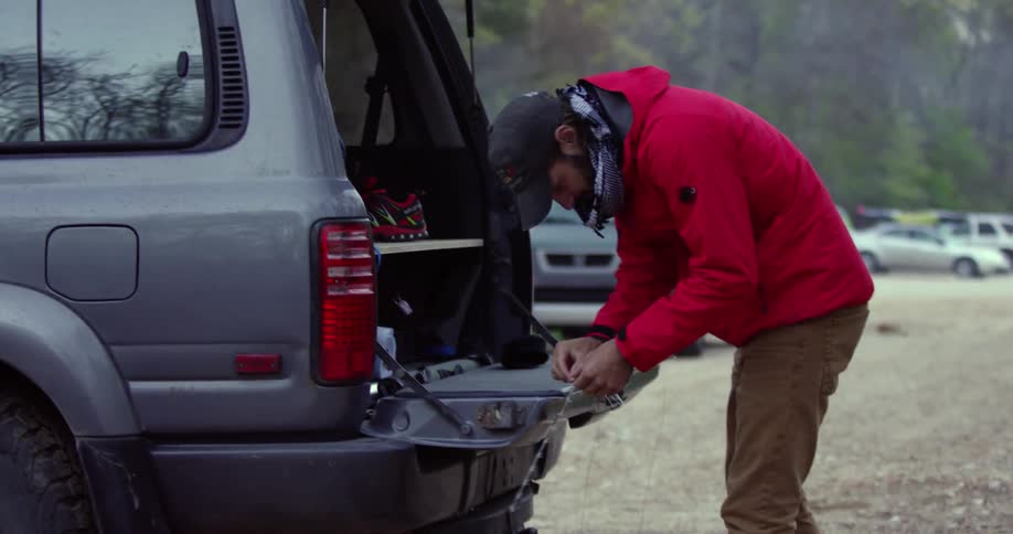 Man working on his fishing pole on the tailgate of his truck
