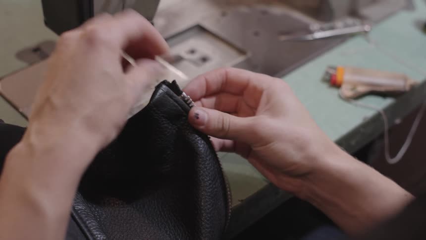 Hands working on a leather jacket and using a lighter
