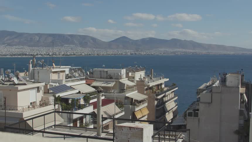 A view of the coastal city of athens with a clear blue sky and mountains in the distance