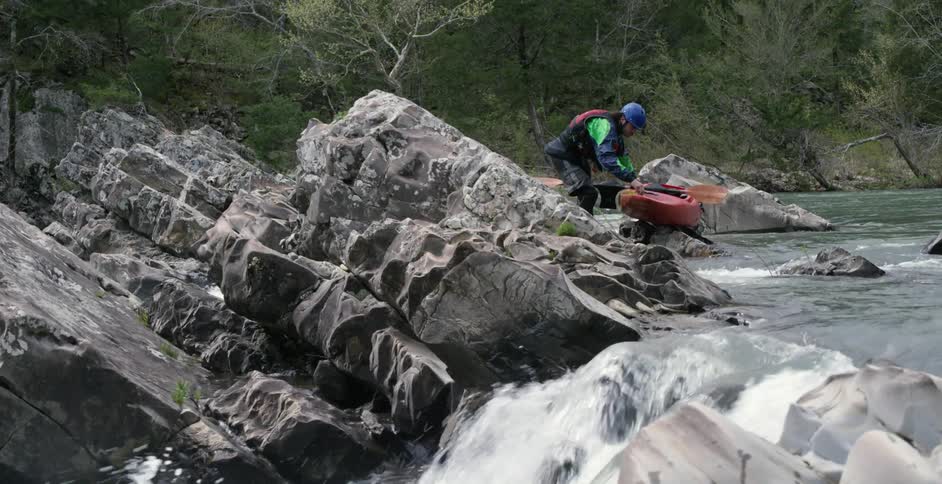 Person picking up paddle off kayak on the river