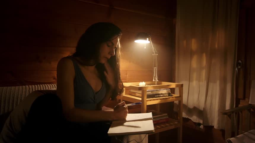 Woman sitting on a sofa writing in a notebook