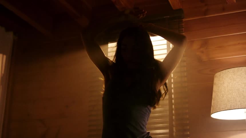 Woman with arms up dancing in a room during the day