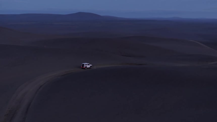 Aerial of a vehicle driving a rural deserted road across the mountains