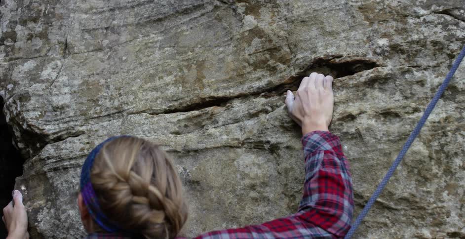 Woman rock climber pulling herself up towards her destiny