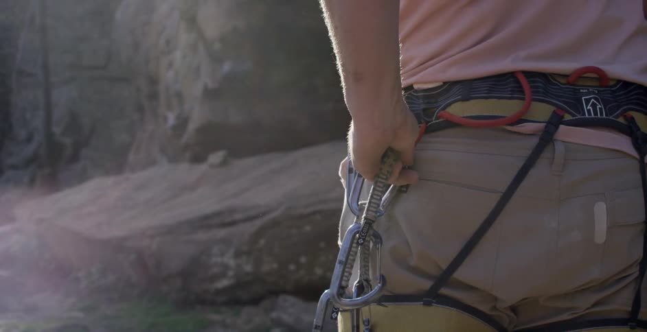 A woman adjusting her rock climbing harness