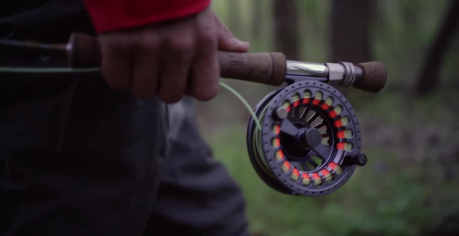 A fisherman carries his rod through the forest