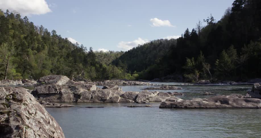 Calm river running through a rocky area on a partly cloudy day