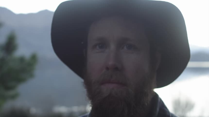 Man wearing a cowboy hat walking slowly outside