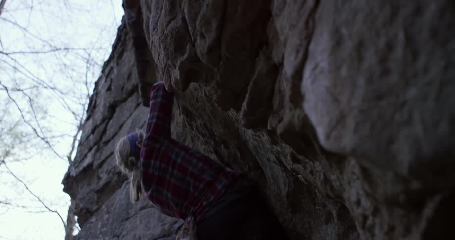 A woman rock climbing on a cloudy day