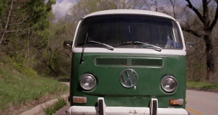 An old vw bus driving down a rural road