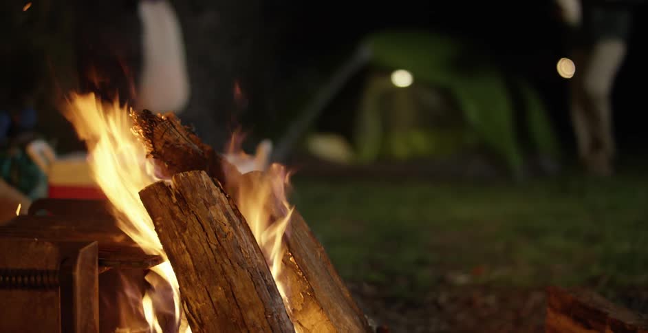 A campfire is burning at a campsite at night