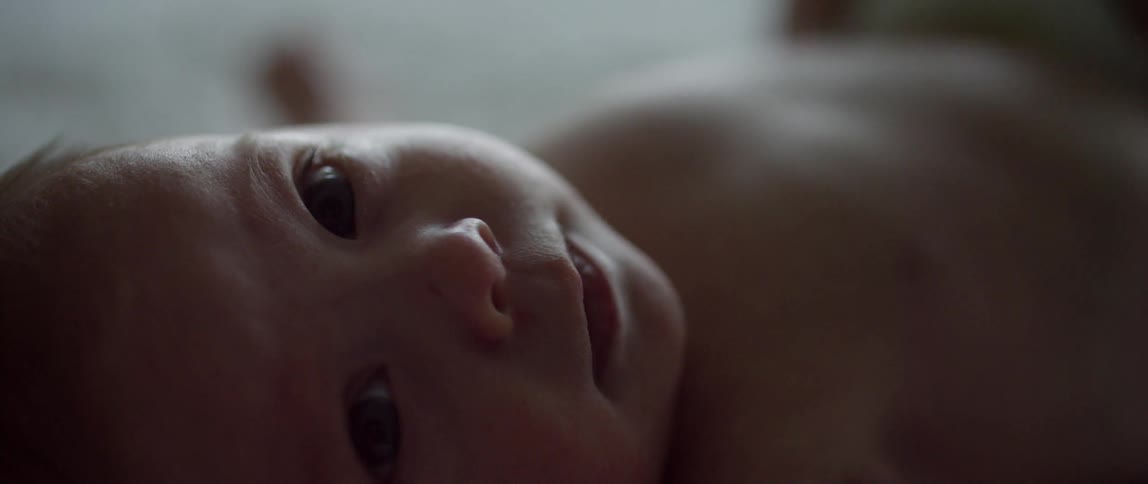 A baby laying down looking at the camera
