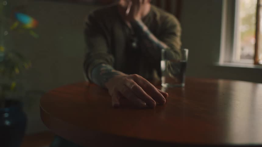 Man with eyes closed sitting at a table looking discouraged
