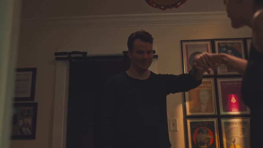 A young couple slow dances in a cozy living room