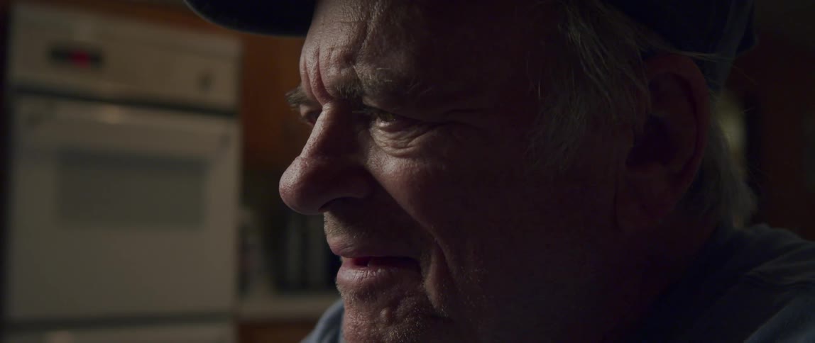 Close up of the face of an elderly man laughing by himself