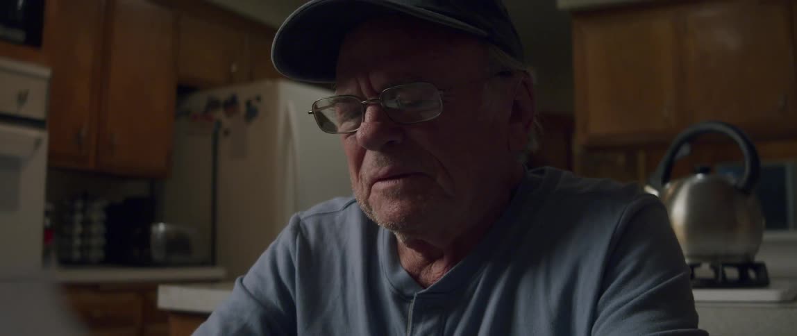 An elderly man looks disappointed as he reads a letter