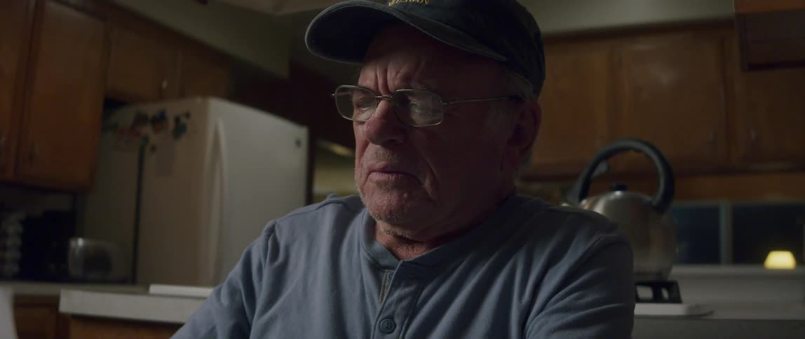 An elderly man looks disappointed as he reads a letter