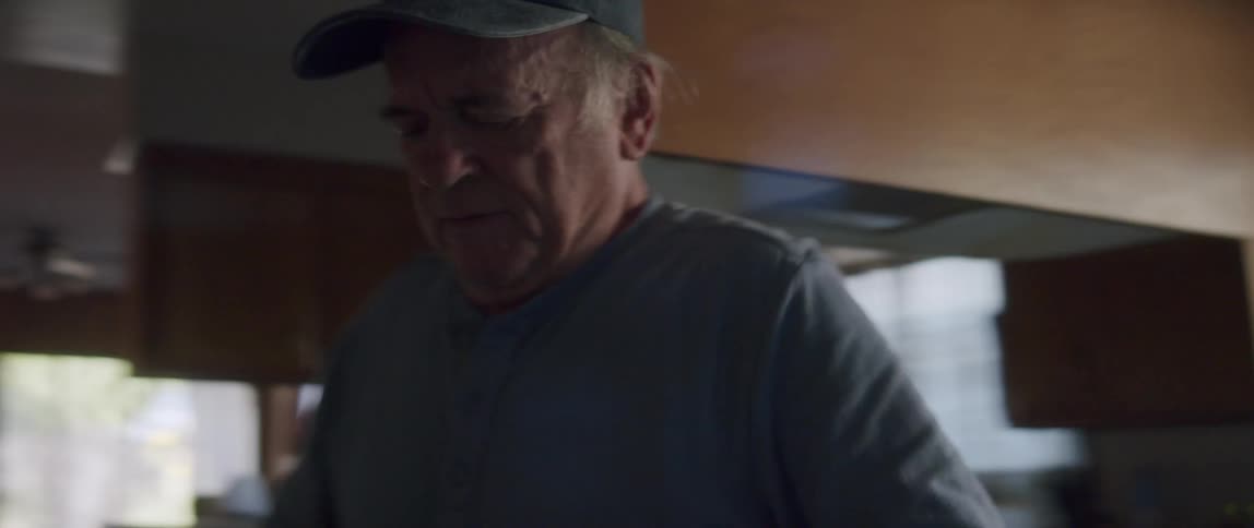 An elderly man moving around the kitchen at home