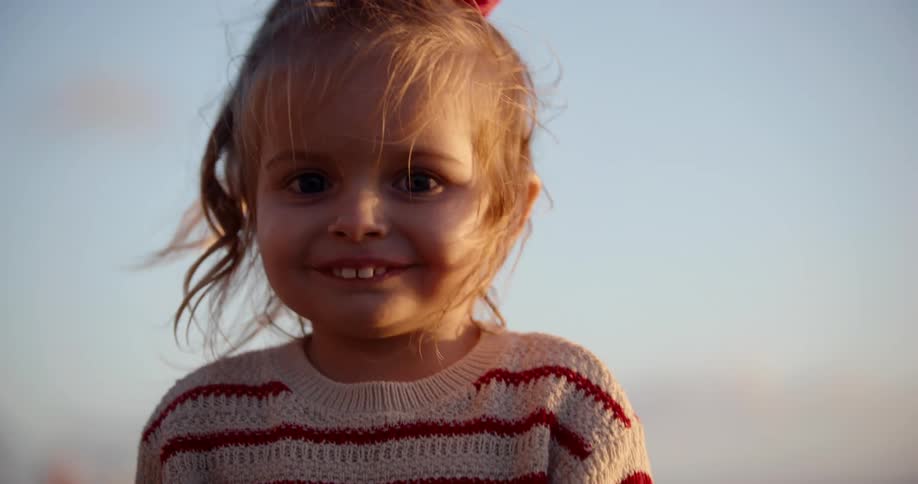 A young girl smiles for the camera on a sunny day