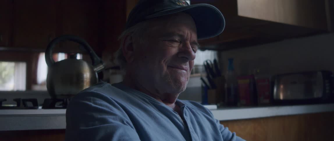 Elderly man sitting at table looking at letter and getting emotional and happy